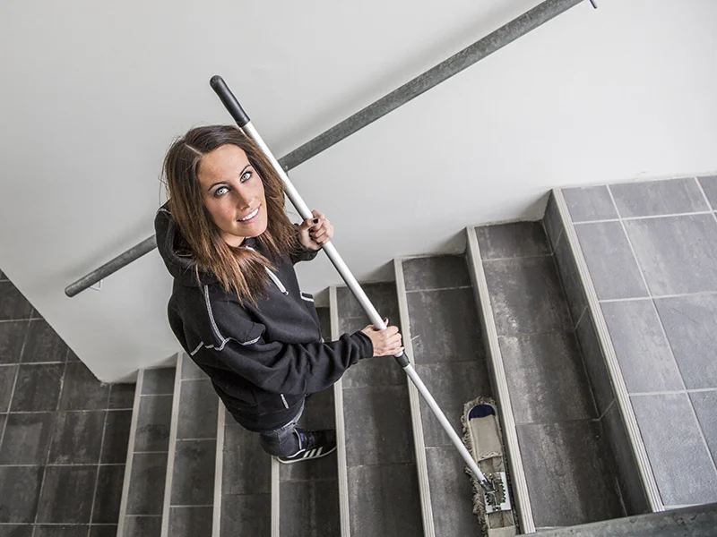 Person rengjør en trapp med en mopp