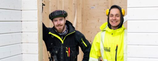 To personer i arbeidsklær med verktøybelte og hørselvern ved trestruktur