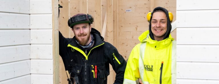To personer i arbeidsklær med verktøybelte og hørselvern ved trestruktur