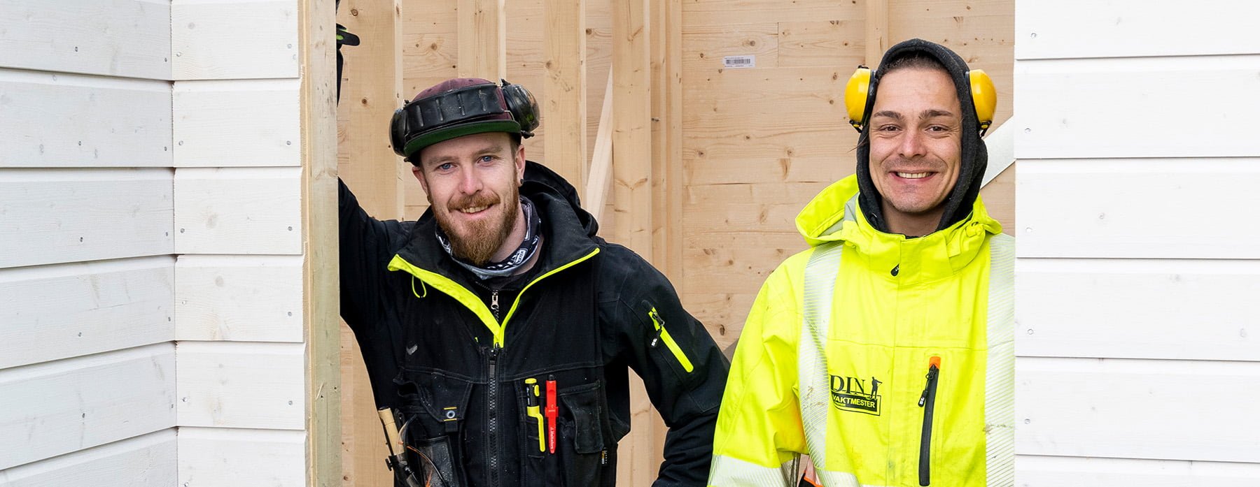 To personer i arbeidsklær med verktøybelte og hørselvern ved trestruktur