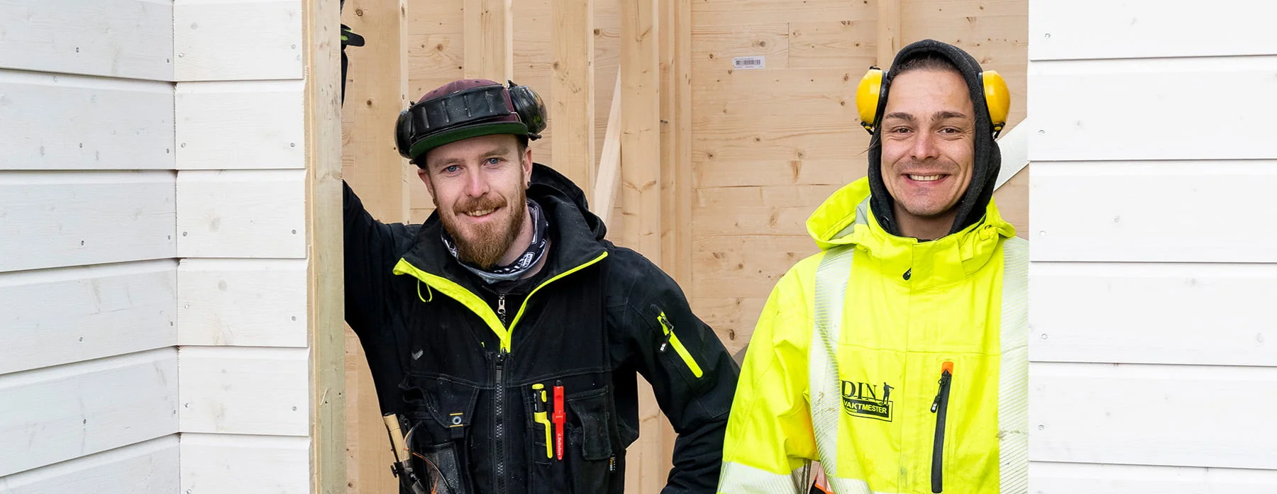 To personer i arbeidsklær med verktøybelte og hørselvern ved trestruktur