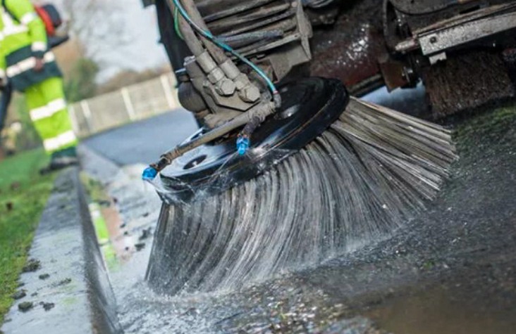 Roterende børste fra feiemaskin rengjør våt asfaltkant