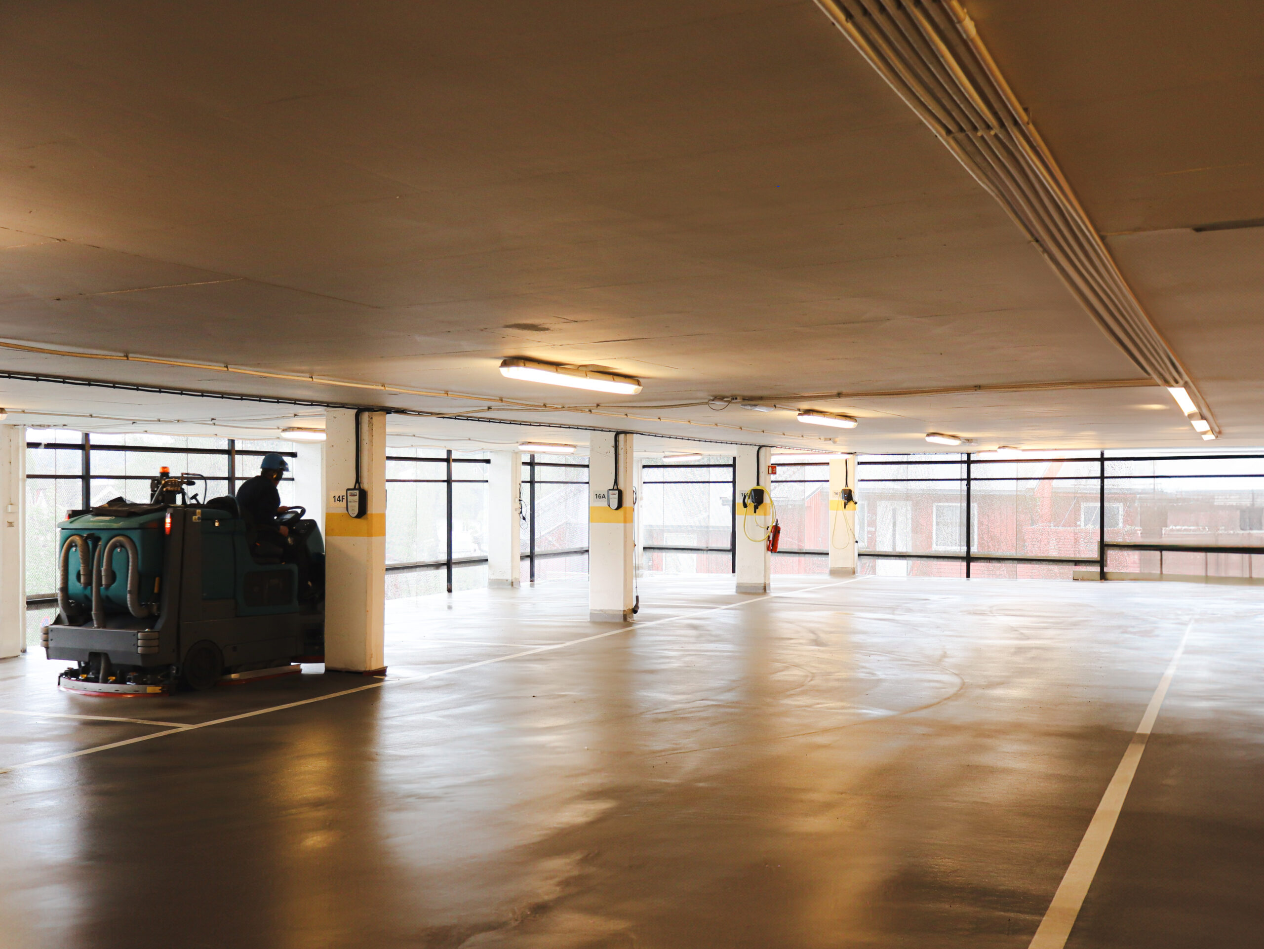 Gulvvaskemaskin rengjør våt betongflate i parkeringshus