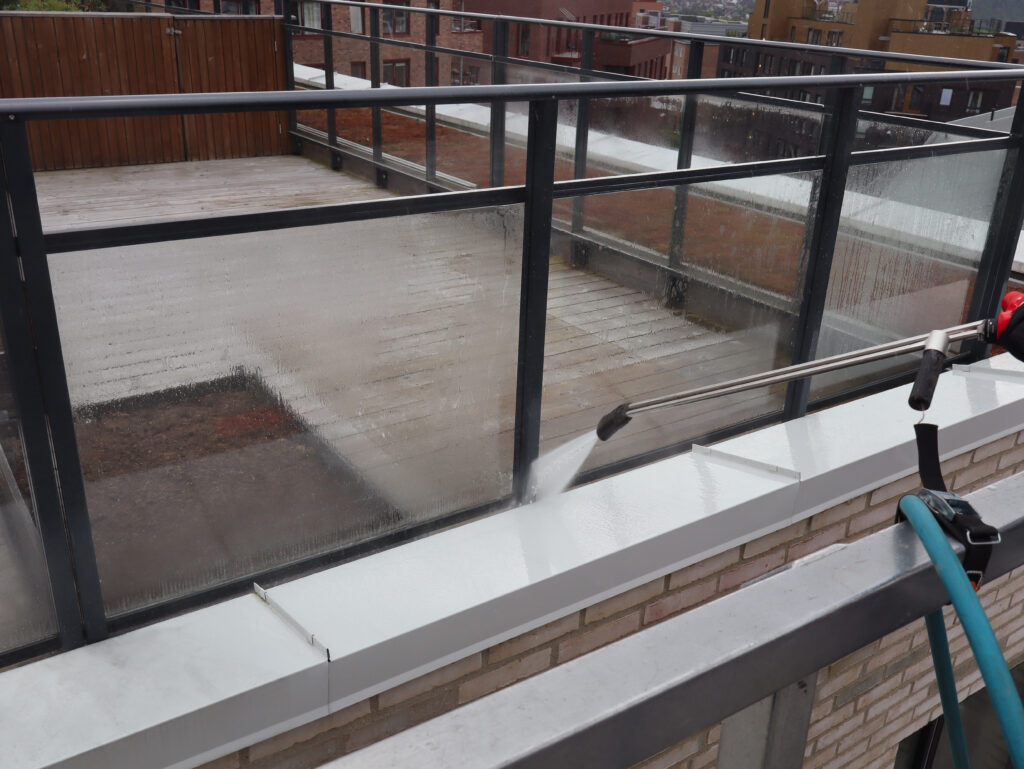 Høytrykkspyling av hvit kant ved glassrekkverk