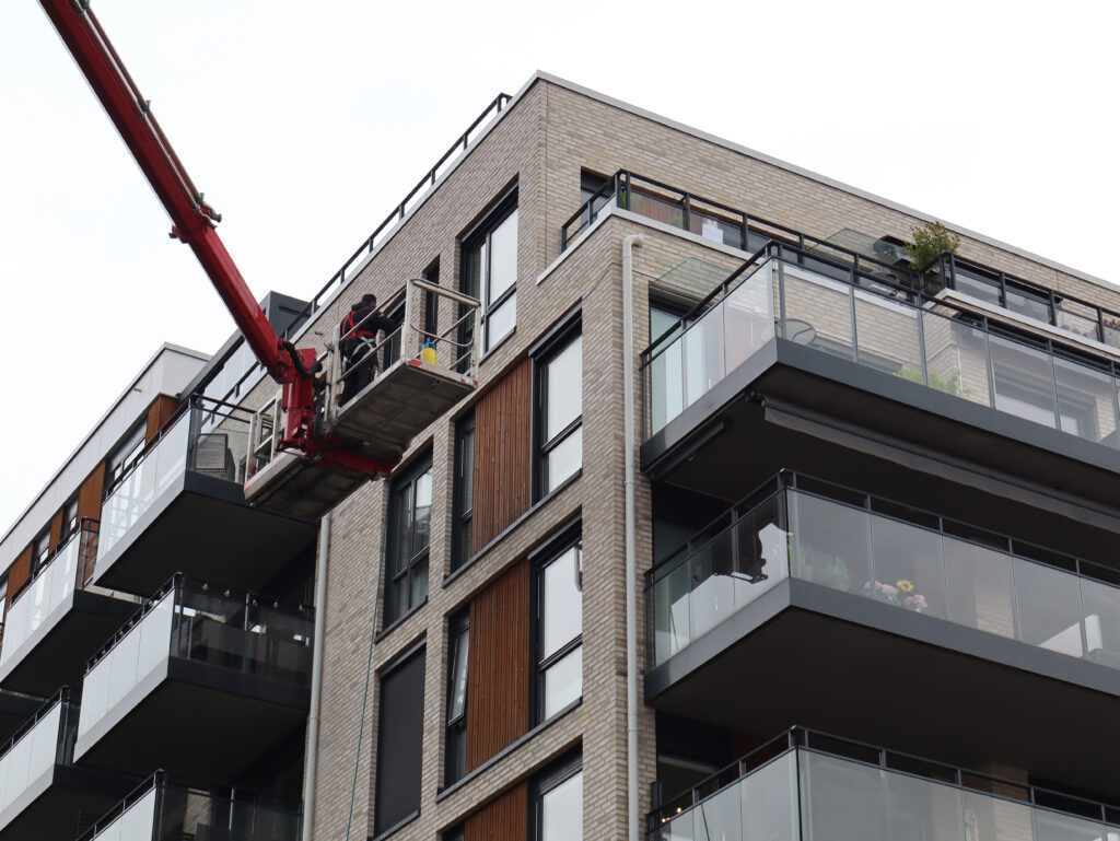Arbeidsplattform på lift ved moderne leilighetsbygg.